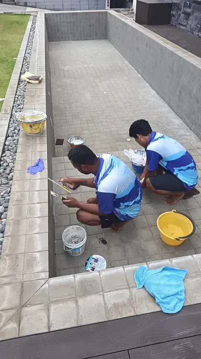 Technicians repairing the edge of an emptied pool